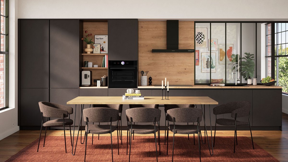 Cuisine moderne élégante avec des armoires noires mates et bois, une grande table en bois entourée de chaises rembourrées, et un éclairage naturel mettant en valeur une verrière et une crédence chaleureuse.